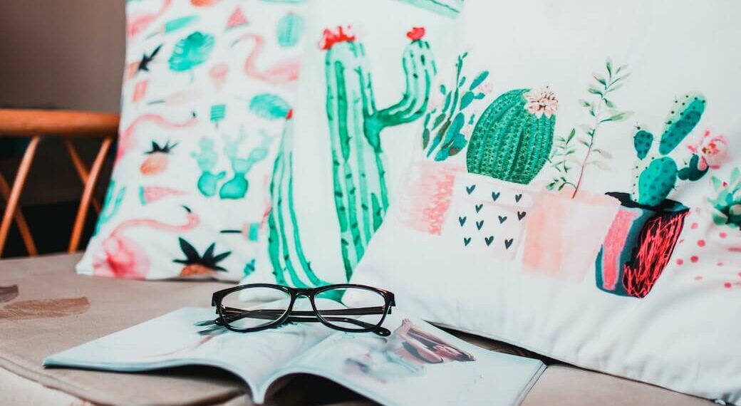 Three pillows on a couch featuring watercolor artwork of cacti.