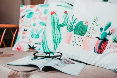 Three pillows on a couch featuring watercolor artwork of cacti.