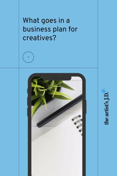 iPhone showing a desk layout with the text "What goes in a business plan for creatives"