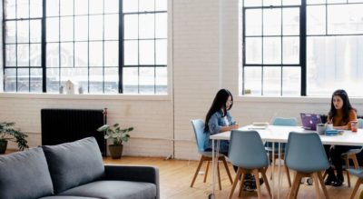 Women working at a conference table in a bright open workspace.