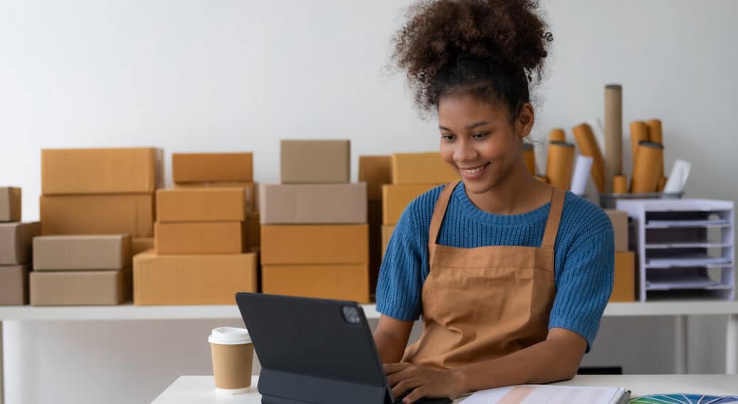 Creative business African American entrepreneur woman smiles and checks online orders.