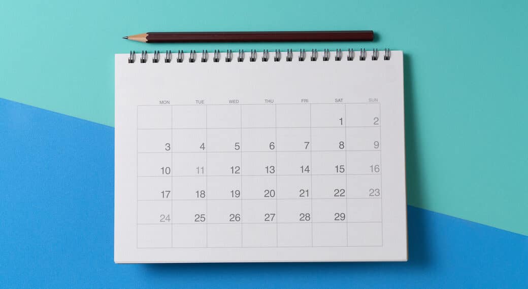 close up of calendar and pencii on the green and blue table background, planning for business meeting or travel planning concept