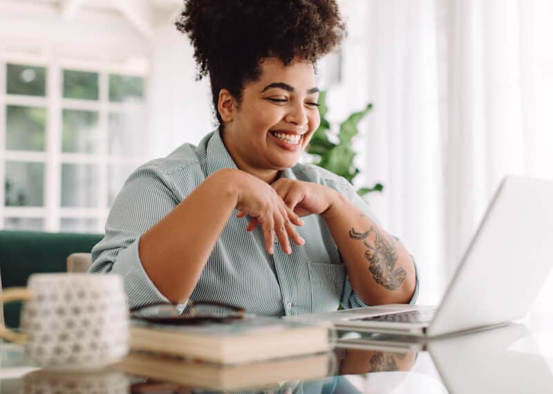 Positive woman video calling using laptop at home