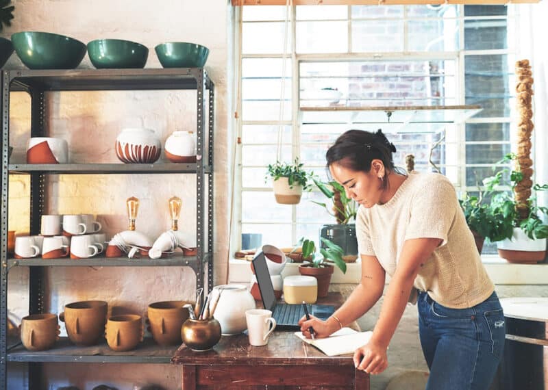 Pottery, owner and woman with writing in workshop for inventory management, order checklist and planning. Small business, artist and notebook for ceramics inspiration, creative ideas and information.