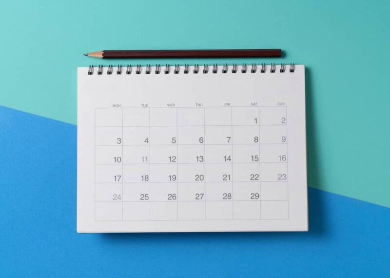 A month calendar on a blue and green background with a pencil.